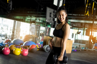 运动美丽的女人锻炼与哑铃重量培训设备与模糊的背景健康的生活和健身房锻炼设备和体育概念与复制空间