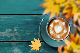 喝咖啡秋天和秋天季节热咖啡拿铁杯蓝色的木表格前视图焦点拿<strong>铁艺</strong>术心形状模糊黄色的枫木叶前景