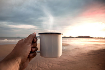 早....咖啡喝热咖啡的海滩在日出手持有杯享受最喜欢的喝和自然开始新一天放松和谐生活生活方式观点视图