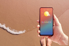 夏天季节概念女人持有移动电话与夏天消息和图标天气沙子海滩与阳光背景前视图
