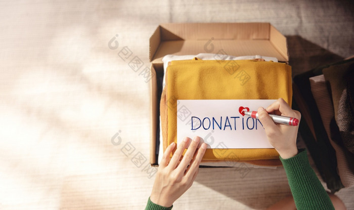 衣服捐赠概念盒子布与捐赠标签女人准备使用老服装首页前视图