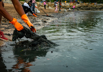 成人和孩子们志愿者收集垃圾的海海滩海滩环境污染整理垃圾海滩人穿橙色手套拉塑料泥的海海滩出
