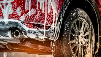 红色的紧凑的运动型多功能车车与体育运动和现代设计洗与肥皂车覆盖与白色泡沫车哪服务业务概念车洗与泡沫之前玻璃打蜡和玻璃涂层汽车