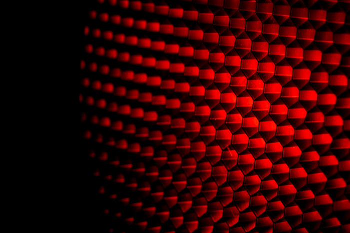 特写镜头蜂窝网格纹理与红色的光红色的和黑暗金属六角形状的模式摘要背景光修饰符设备金属蜂窝未来主义的模式蜂蜜网格细胞网络