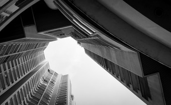 底视图摩天大楼建筑对灰色的天空和云看视图公寓建筑的城市真正的房地产和企业建设多层住宅建筑公寓