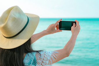年轻的亚洲女人穿他使用智能手机采取照片热带海滩夏天假期热带天堂海滩快乐赶时髦的人女孩旅行假期女人享受和放松生活夏天共鸣