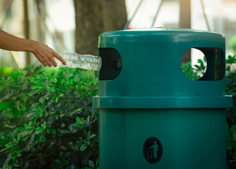 人手扔空水瓶回收本公园绿色塑料回收本男人。丢弃瓶垃圾本浪费管理塑料瓶垃圾减少和重用塑料概念