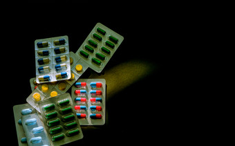 色彩斑斓的抗生素胶囊药片泡包黑暗背景与复制空间医学为感染疾病抗生素药物使用与合理的药物电阻和医疗保健概念