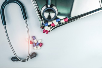 绿色听诊器与桩抗生素胶囊药片白色表格附近药物托盘抗菌药物电阻和过度使用医疗设备为医生临床心脏病学概念健康哪