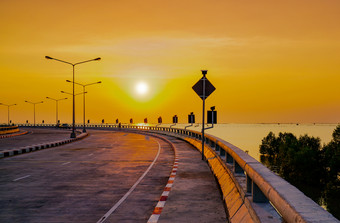 弯曲的沿海路与街灯和橙色天空日落春武里泰国