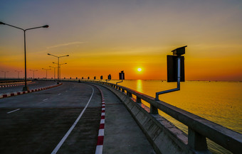 弯曲的沿海路与街灯和橙色天空日落春武里泰国