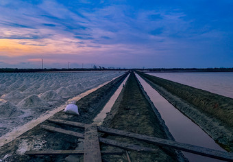 盐农场的早....与日出天空和云景观海盐场泰国海水运河和土壤通路农场生材料盐工业夏天旅游泰国