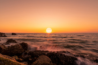 大太阳<strong>天际线</strong>日落海洋水飞溅岩石海滩与美丽的日落天空和橙色<strong>云海</strong>波溅石头海海岸夏天自然景观热带海景