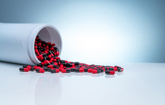 红黑抗生素胶囊药片传播出白色塑料药物瓶梯度背景制药行业抗生素药物电阻概念医疗保健和制药学概念