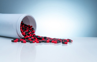 红黑抗生素胶囊<strong>药片</strong>传播出白色塑料药物瓶梯度背景制药行业抗生素药物电阻概念医疗保健和制药学概念