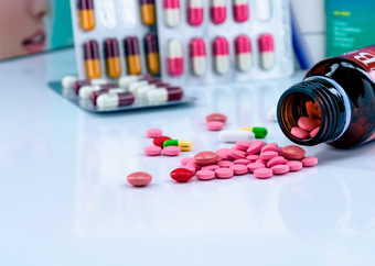 平板电脑药片传播出琥珀色的玻璃药物瓶模糊胶囊泡包红色的和粉红色的平板电脑药物治疗使用概念止痛药医学制药行业药店产品