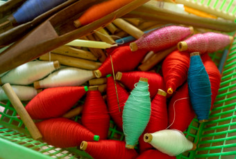 前视图色彩斑斓的纱线线轴和空木线轴塑料篮子纱线编织航天飞机工具纺织织物织工具设备为传统的编织织机布生产