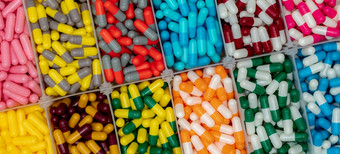 色彩斑斓的胶囊药片塑料盒子制药行业粉红色的黄色的蓝色的绿色橙色灰色的红色的和白色胶囊药片医疗保健和医学维生素和补充概念