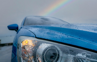 前面视图蓝色的奢侈品运动型多功能车车停附近海海滩多雨的一天与彩虹背景雨滴蓝色的纹理车阀盖车打开头灯光坏天气为安全开车