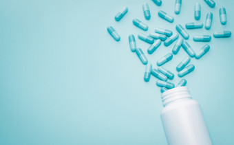 蓝色的胶囊药片传播出白色塑料药物瓶蓝色的背景药店网络横幅抗生素药物电阻超级细菌概念健康预算和政策抗生素药物过度使用
