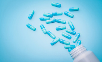 蓝色的抗生素胶囊药片传播出塑料药物瓶蓝色的背景抗生素药物电阻抗菌药物过度使用处方药物制药行业健康预算