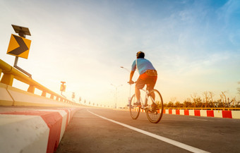 模糊回来视图男人。穿头盔骑自行车为锻炼曲线路交通标志与人骑自行车自行车的路户外活动夏天健康的生活方式体育运动和活动