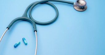 蓝色的胶囊药片和绿色听诊器蓝色的背景健康检查心脏病学医生设备为心跳测试医疗保健和医疗概念诊断医疗工具为诊断