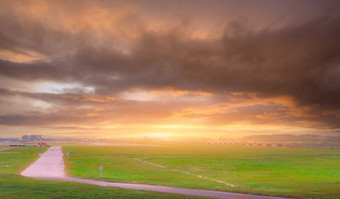 景观绿色草场的机场模糊跑道与商业飞机被取从着陆和橙色阳光灰色的多云的天空航空业务路的机场附近跑道