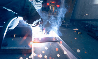 焊机焊接金属与氩弧焊接机和有焊接火花和烟男人。穿保护手套安全工业工作场所焊机工作与安全钢行业技术