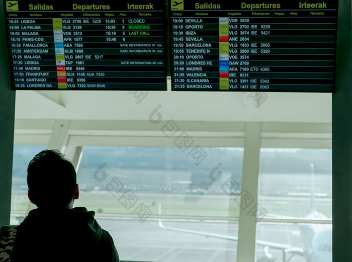男人。看信息离开董事会和检查他的飞行的机场为旅行欧洲乘客看时间表数字显示机场终端旅游与延迟飞行