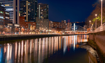 城市景观现代建筑的晚上附近的河和桥现代体系结构办公室建筑摩天大楼建筑与晚上光街灯业务和金融中心建筑