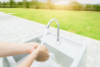女人洗手与利用水下水龙头白色水槽洗手与利用水户外水槽附近草场个人卫生防止冠状病毒科维德健康的生活方式