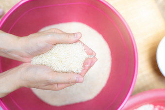 前视图女人手持有大米以上红色的塑料碗全球食物危机生干大米未煮过的磨碎的白色大米天课和慈善机构概念有机麦片粮食大米价格世界市场
