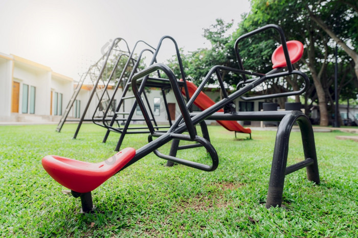 红色的跷跷板的操场上操场上设备为孩子们玩塑料跷跷板跷跷板摇摆不定的和幻灯片户外操场上与绿色草地面户外孩子们玩具公园