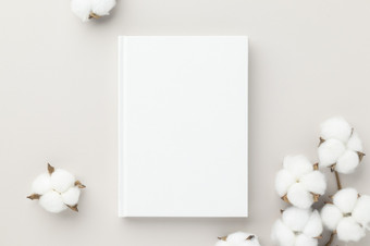 白色书空白封面模型米色背景与棉花花平躺模型