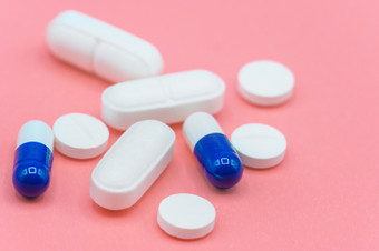 各种各样的白色和蓝色的药片粉红色的背景与复制空间不同的医疗药物各种各样的白色和蓝色的药片粉红色的背景与复制空间不同的医疗药物