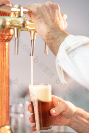 倒啤酒为客户端酒保倒啤酒而站的酒吧计数器倒啤酒为客户端酒保倒啤酒而站的酒吧计数器