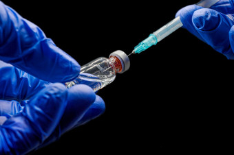 关闭医生手准备的注射器和瓶为疫苗接种黑色的孤立的背景关闭医生手准备的注射器和瓶为疫苗接种黑色的孤立的背景