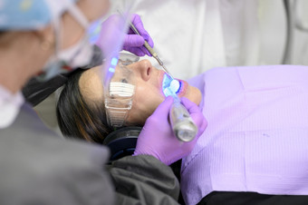 年轻的女人接收紫外线光为美白过程牙医办公室高质量照片年轻的女人接收紫外线光为美白过程牙医办公室