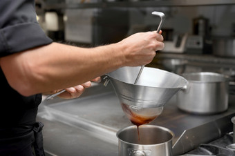 烹饪的餐厅厨房筛选酱汁通过筛老板过滤酱汁高质量照片烹饪的餐厅厨房筛选酱汁通过筛老板过滤酱汁