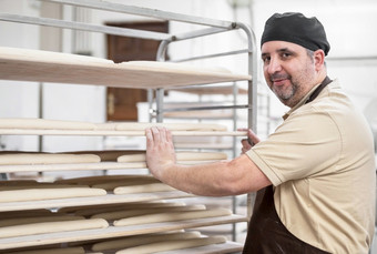 自信贝克摆姿势与架新鲜的面包面包面包店高质量照片自信贝克摆姿势与架新鲜的面包面包面包店