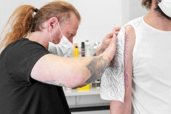 熟练的纹身艺术家把草图的手臂男人。高质量照片熟练的纹身艺术家把草图的手臂男人。