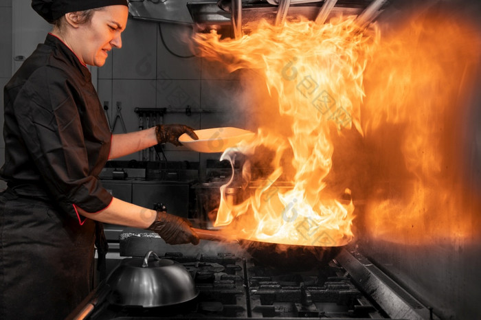 女人老板烹饪锅的厨房烹饪燃烧的锅与蔬菜的商业厨房高质量摄影女人老板烹饪锅的厨房烹饪燃烧的锅与蔬菜的商业厨房