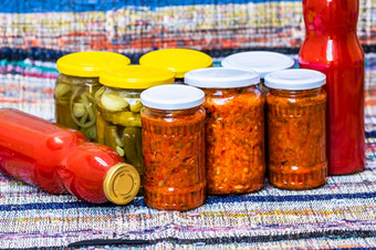 玻璃罐子与腌红色的贝尔辣椒和腌黄瓜泡菜孤立的罐子与各种腌蔬菜罐子与扎库斯卡和瓶与西红柿酱汁保存食物概念