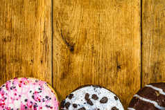色彩斑斓的甜甜圈木表格甜蜜的糖衣糖食物与上釉洒甜甜圈与巧克力结霜前视图与复制空间