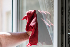 男人。擦拭窗口使用红色的超细纤维地毯清洁服务概念做家务和管家概念