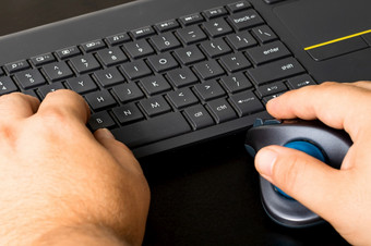 手使用鼠标和键盘手电脑鼠标和键盘黑色的木背景