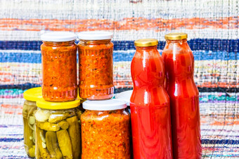 玻璃罐子与腌红色的贝尔辣椒和腌黄瓜泡菜孤立的罐子与各种腌蔬菜罐子与扎库斯卡和瓶与西红柿酱汁保存食物概念