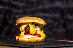 细节新鲜的美味的牛肉芝士汉堡与融化了奶酪孤立的黑色的背景