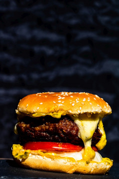 细节新鲜的美味的牛肉芝士汉堡与融化了奶酪孤立的黑色的背景